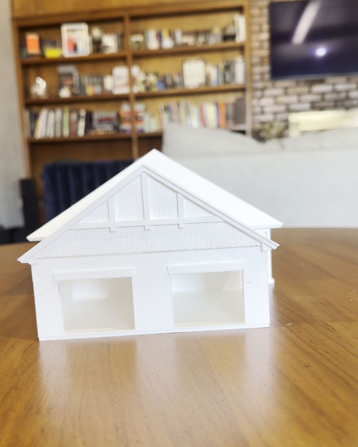 Front gable of the white 3D printed Aurora Duplex model on a wooden table