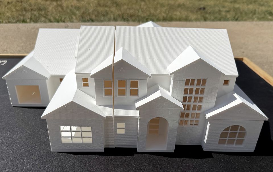 Front elevation of the Adeline model with the roof on: stacked gables, an arched entry and a tall window grid
